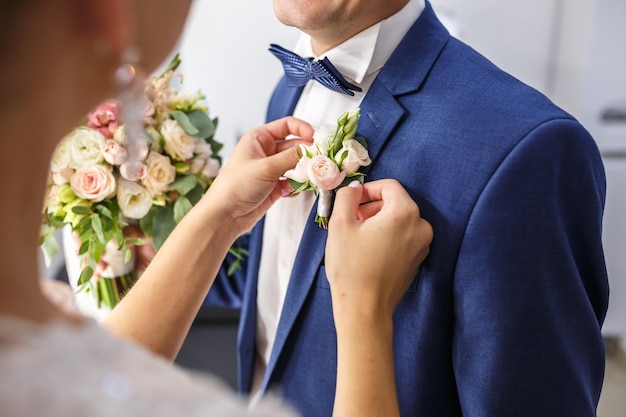 Noiva coloca noivo na lapela de rosas brancas no dia do casamento