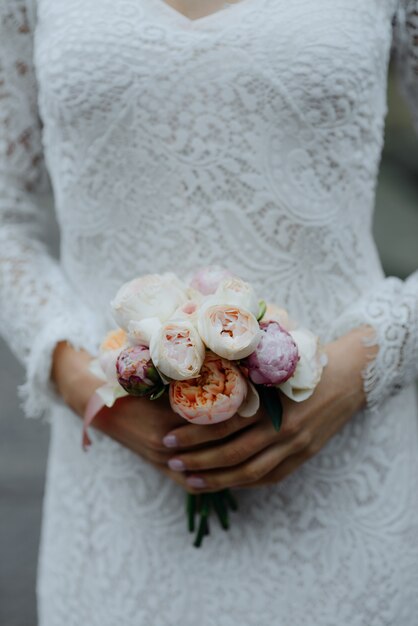 Foto noiva com flores na mão ao ar livre.