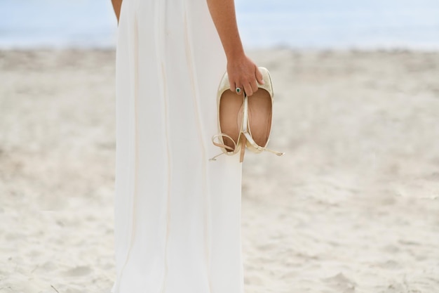 Noiva de vestido branco e sapatos dourados na praia