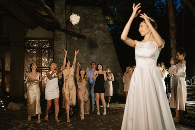 Noiva de vestido branco lança um buquê de casamento