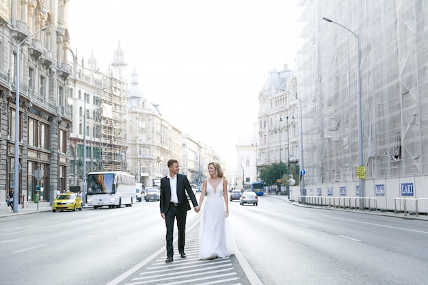 Noiva e noivo abraçando na rua da cidade velha. casal de noivos apaixonados. vestido de strass de luxo.