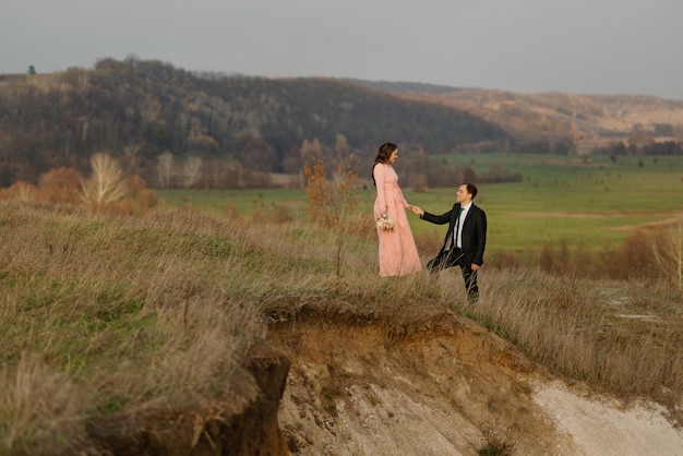 Noiva e noivo andando em uma área montanhosa com uma bela vista.