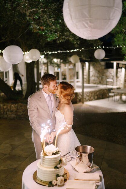 Foto noiva e noivo beijam e cortam o bolo de casamento