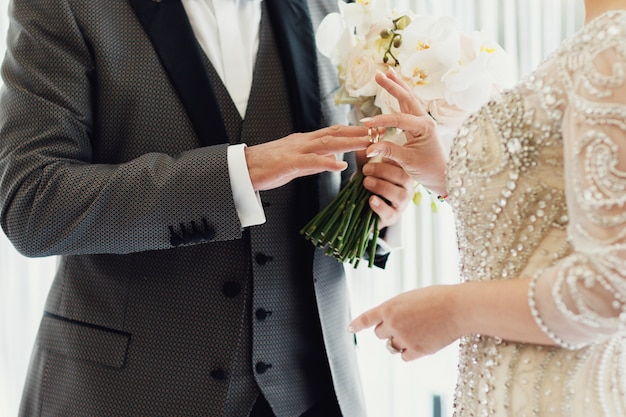 Noiva e noivo com aliança e buquê de flores frescas
