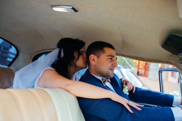 Noiva e noivo dentro de um carro clássico. eles estão felizes.