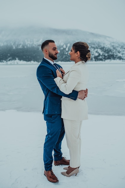 Noiva e noivo entre a montanha nevada Eles estão de pé e abraçando o casamento de inverno ao ar livre Fechar