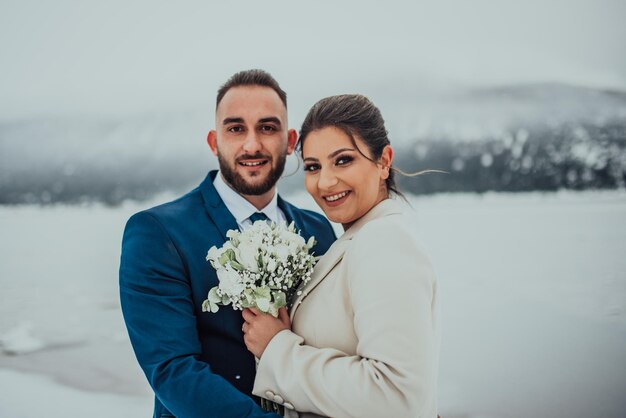 Noiva e noivo entre a montanha nevada Eles estão de pé e abraçando o casamento de inverno ao ar livre Fechar