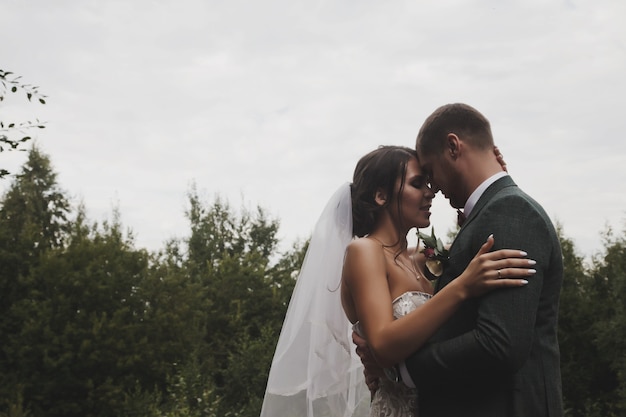 Noiva e noivo estilo irlandês no dia do casamento, caminhar ao ar livre na casa de aldeia do país. Homem e mulher feliz recém-casado casal nupcial caminhar no parque verde ou florestal. Conceito de dia do casamento e casamento