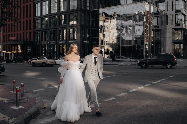 Noiva e noivo europeus elegantes andando na rua da cidade a noiva em um vestido da moda