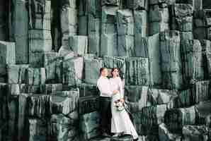 Foto noiva e noivo ficam nas rochas negras de reynisdrangar na islândia