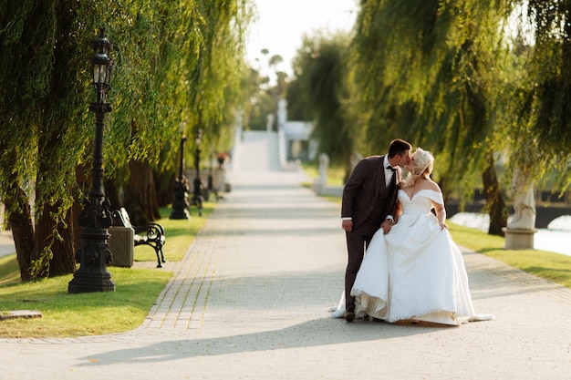 Noiva e noivo no casamento dia caminhando ao ar livre na natureza da primavera. Casal nupcial, mulher feliz recém-casado e homem abraçando no parque verde. Casal apaixonado casamento ao ar livre.