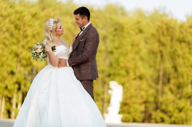 Noiva e noivo no casamento dia caminhando ao ar livre na natureza da primavera. Casal nupcial, mulher feliz recém-casado e homem abraçando no parque verde. Casal apaixonado casamento ao ar livre.