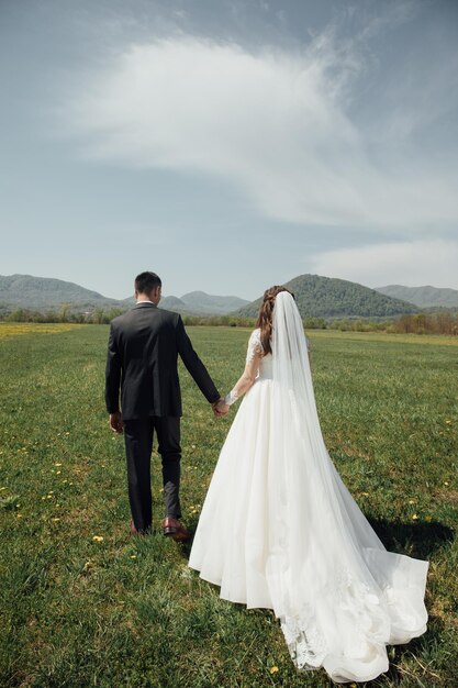 Noiva e noivo no dia do casamento andando ao ar livre na natureza verde de verão.