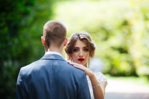 Noiva e noivo no dia do casamento, caminhando ao ar livre na natureza.