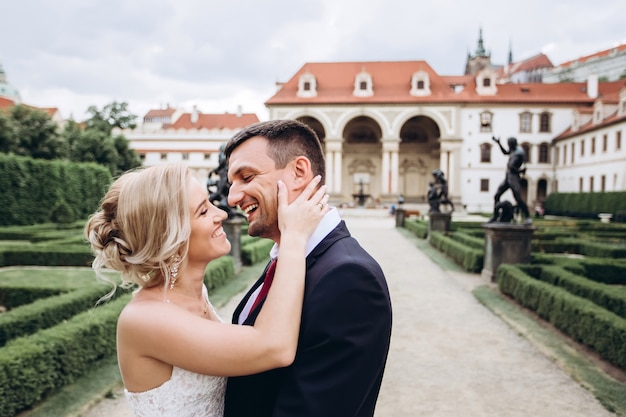 Noiva e noivo se abraçando, beijo ao ar livre no dia do casamento, jovem casal caminhando em Praga, dia dos namorados