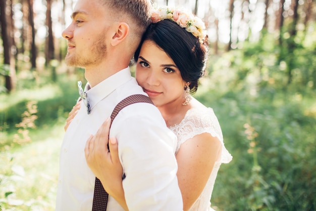 Noiva e noivo se abraçando no dia do casamento, jovem casal feliz se beijando no parque na natureza, dia dos namorados