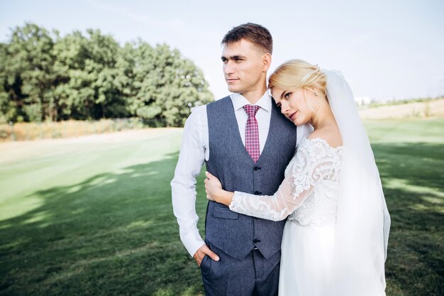 Noiva e noivo se abraçando, se beijando ao ar livre em um dia de casamento, jovem casal, dia dos namorados