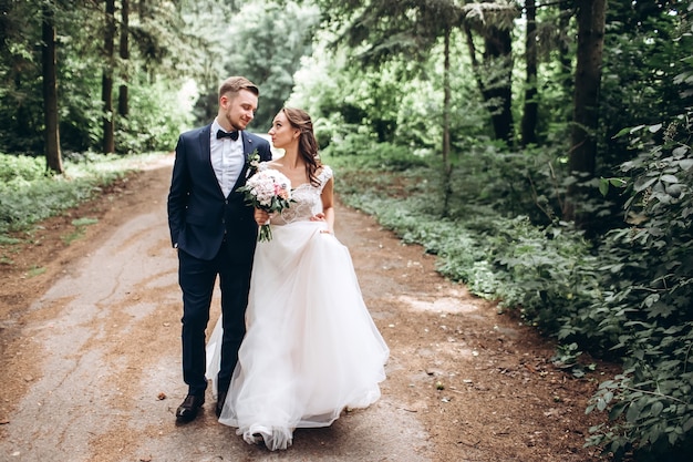 Noiva e noivo se abraçando, se beijando ao ar livre em um dia de casamento, jovem casal, dia dos namorados