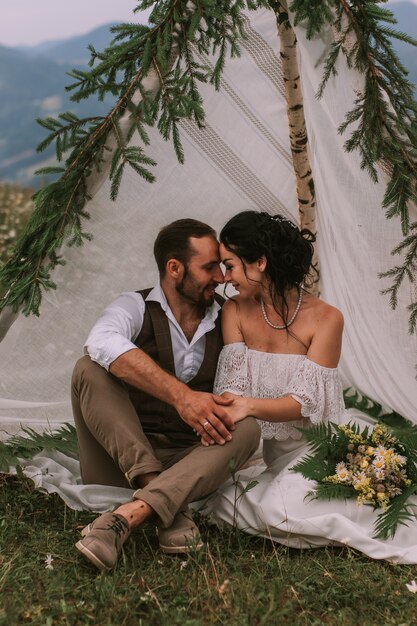 Noiva e noivo sentados em uma cabana de casamento