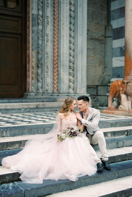 Noiva e noivo sentam-se nos degraus da igreja bergamo itália