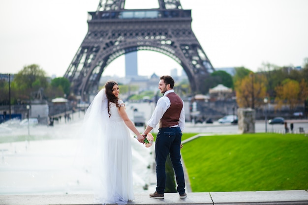 Noiva e noivo, tendo um momento romântico no dia do casamento em Paris, em frente à turnê Eiffel