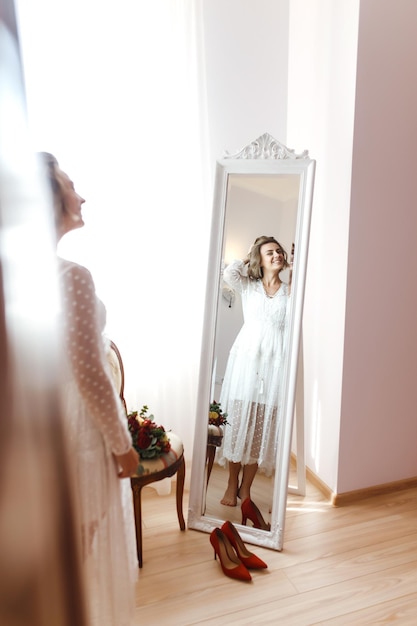 Noiva elegante vestido branco olhando no espelho A noiva sorri e posa na frente do espelho