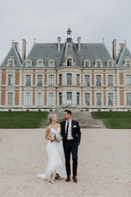 Noiva em um lindo vestido de noiva, noivo em um elegante smoking, vá para o antigo castelo na França