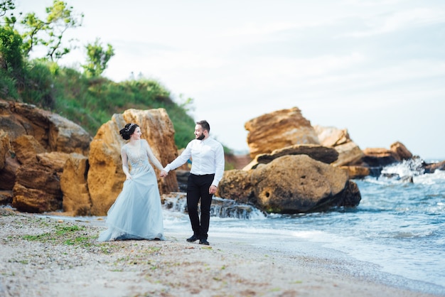 noiva em um vestido azul caminhar ao longo da costa do oceano