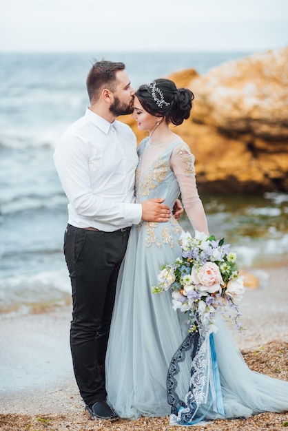 Noiva em um vestido azul caminhar ao longo da costa do oceano