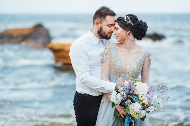 Noiva em um vestido azul caminhar ao longo da costa do oceano