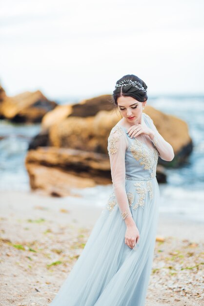 Noiva em um vestido azul claro caminhando à beira-mar