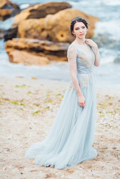Noiva em um vestido azul claro caminhando à beira-mar