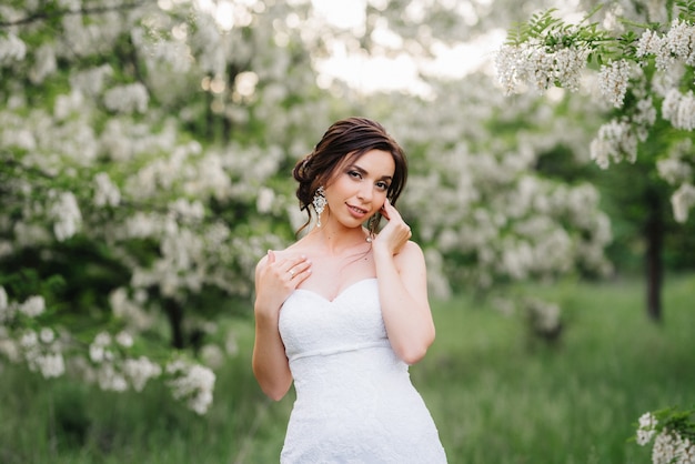 Noiva em um vestido branco com um grande buquê de primavera em uma floresta verde