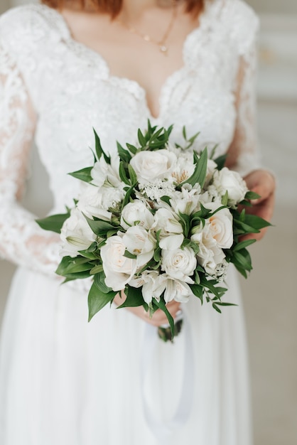 Noiva em um vestido branco com um lindo buquê de casamento em close-up de mãos