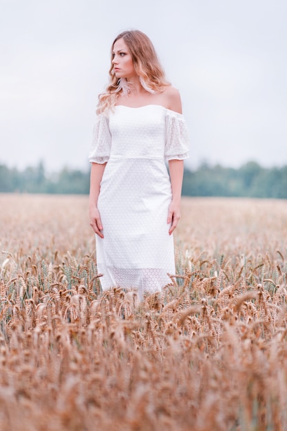 Noiva em um vestido branco posando em um campo de trigo