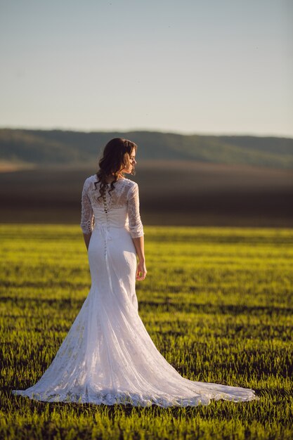 Noiva em um vestido de noiva de renda em pé em um campo