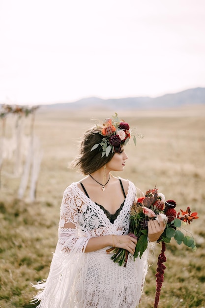 Noiva em uma coroa de flores com um buquê de flores em um campo