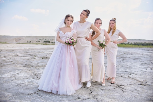 Noiva feliz e damas de honra posando no deserto