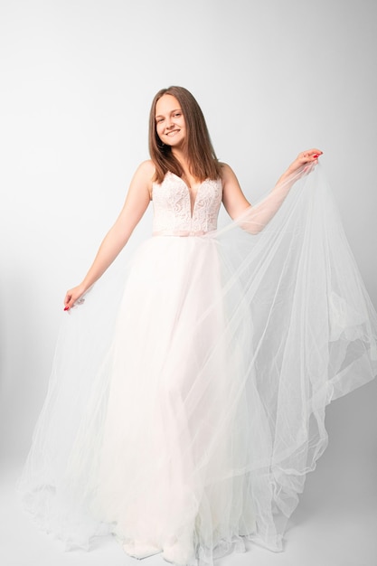 Noiva feliz. Elegância feminina. Dia do casamento. Filmagem do evento. Mulheres sorridentes em vestido de organza fofo branco posando na câmera em estúdio isolado na luz.