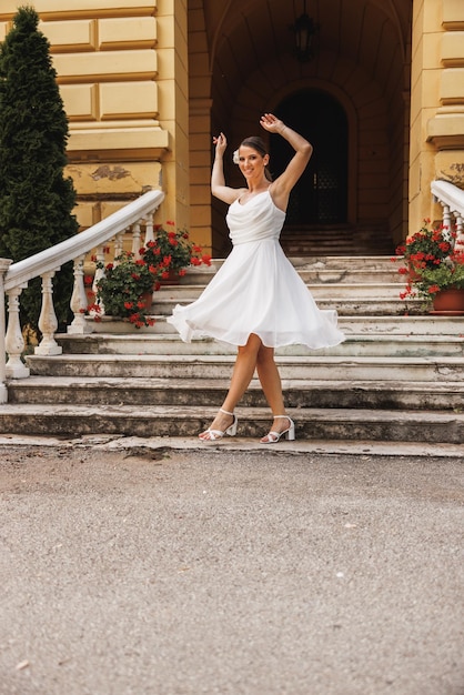 Noiva incrível em lindo vestido de noiva branco se divertindo e dançando ao ar livre no dia do casamento.