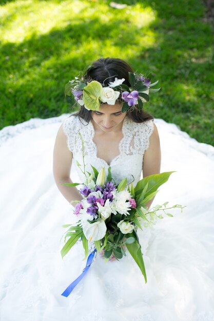 Foto noiva jovem bonita em uma coroa de flores com um buquê na mão