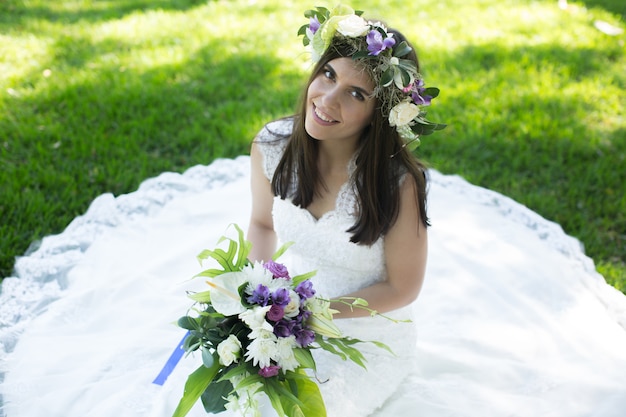 Noiva jovem bonita em uma coroa de flores com um buquê na mão
