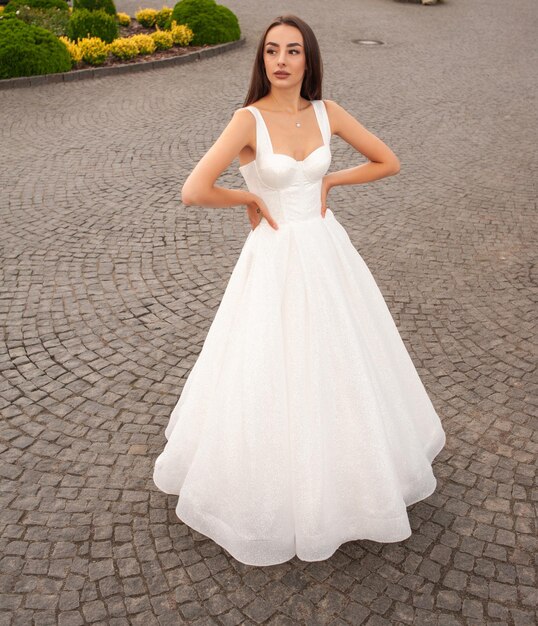 Noiva jovem de moda em vestido de noiva elegante ao ar livre