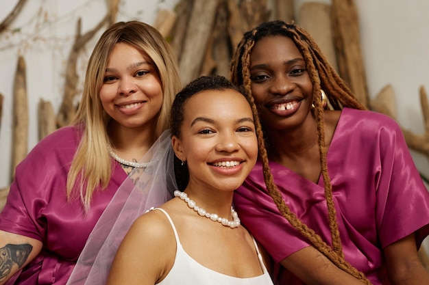 Foto noiva jovem se divertindo com damas de honra durante o casamento e olhando para a câmera