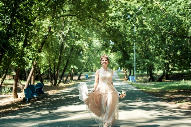 Noiva linda em um vestido bege com uma saia-ritmo andando no parque