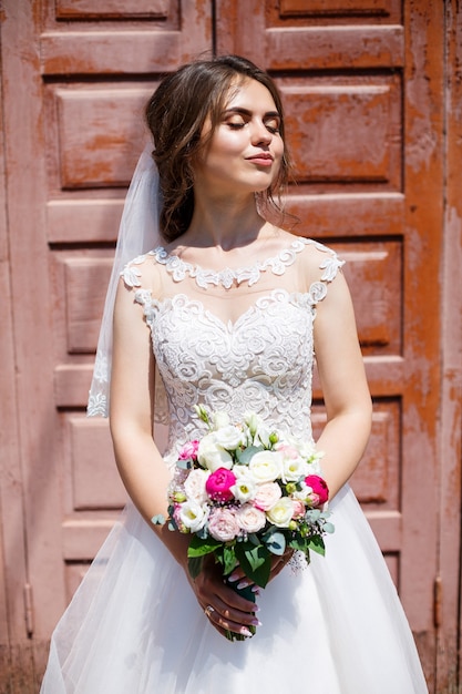 Noiva linda em um vestido branco e véu posando lindamente e sorrindo em um dia de casamento