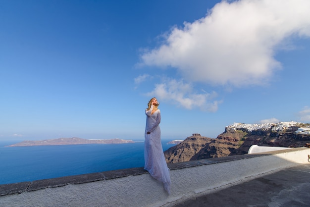 Noiva linda em um vestido branco posando no contexto do mar Mediterrâneo em Thira, Santorini.