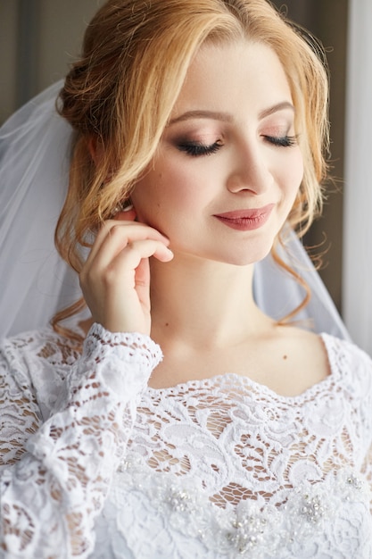 Noiva linda no vestido de casamento branco no dia do casamento. Uma mulher está esperando seu noivo antes da cerimônia de casamento. mulher com um véu na cabeça