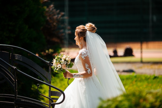 Noiva linda no vestido de casamento de moda em plano de fundo natural. A noiva jovem deslumbrante é incrivelmente feliz. Dia do casamento