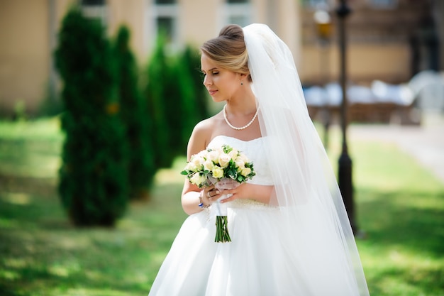 Noiva linda no vestido de casamento de moda em plano de fundo natural. A noiva jovem deslumbrante é incrivelmente feliz.